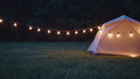 glowing string lights illuminate a tent nestled in a grassy meadow, creating a magical and inviting ambiance for a nighttime camping experience