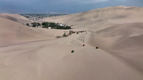 Desert-oasis-Huacachina,-Peru-with-lake-and-palms,-with-great-sand-dunes-in-the-background