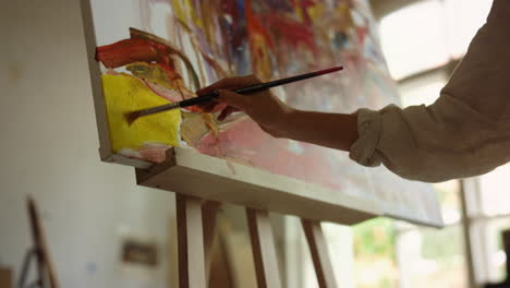 inspired woman making brush stroke on canvas. talented girl drawing indoors.