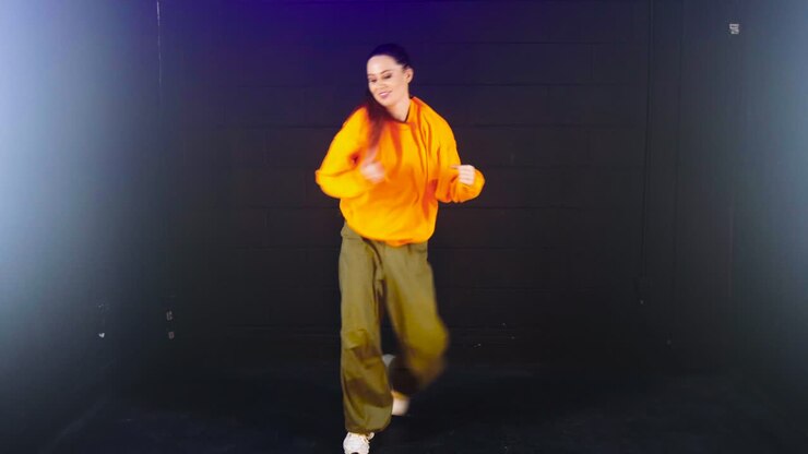 Talented Woman in Baggy Clothes Dancing in Studio with Black Background