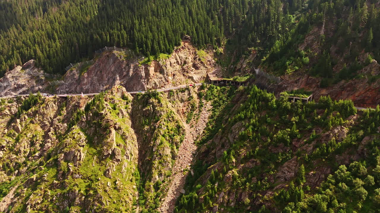 Mountain road through rocky cliffs in Romania. Curved road passing through rocky cliffs and pine forest in the Carpathian Mountains of Romania