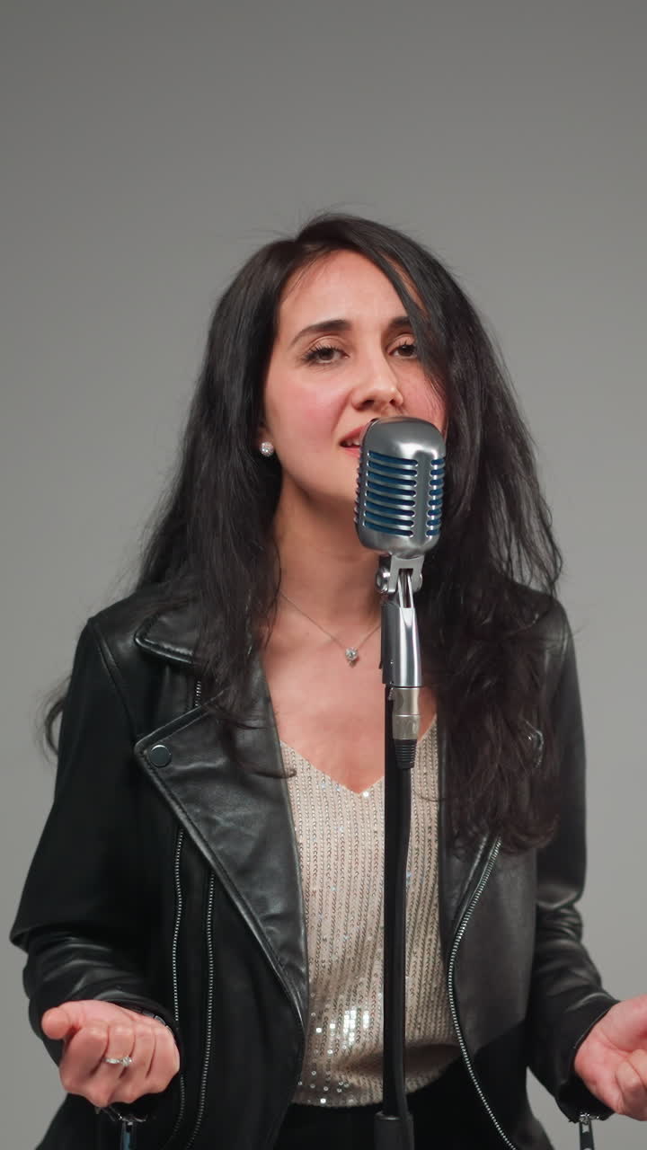 희미한 여성 보컬이 부드럽게 그녀의 머리를 부드러운 초점 배경에 대한 빈티지 마이크 앞에 움직이는 클로즈업