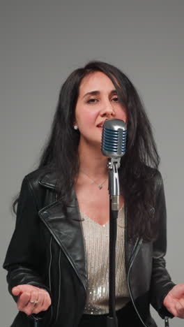 primer plano de una vocalista femenina borrosa moviendo suavemente la cabeza frente a un micrófono vintage contra un fondo de enfoque suave