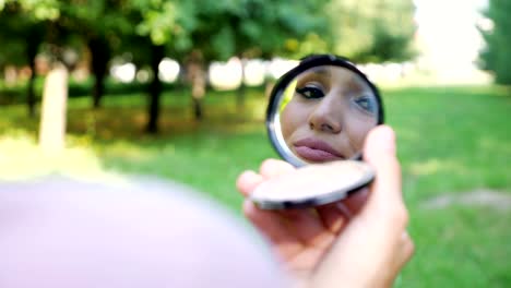 elegant young woman in pink hijab reflected in small mirror