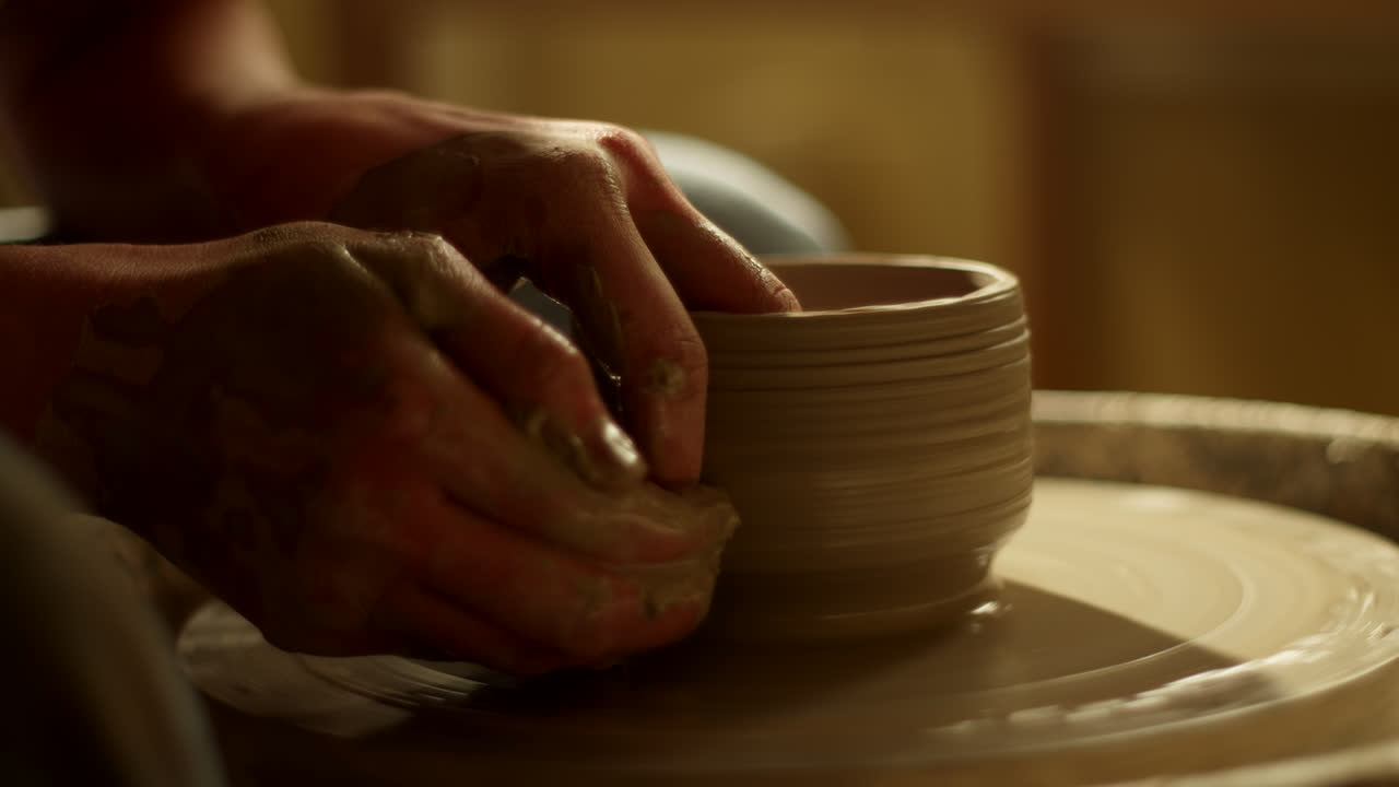 Hands shaping a clay pot on a pottery wheel