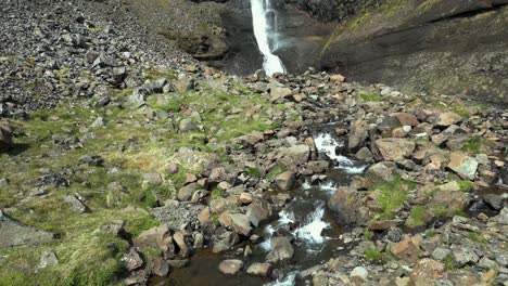 Flying-towards-and-above-a-small-Waterfall-surrounded-by-meadows