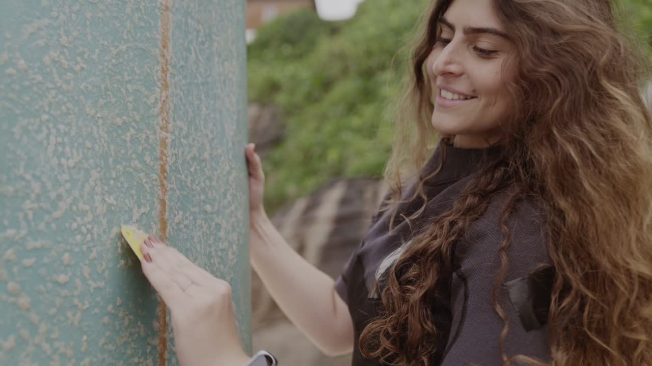 Woman waxing a surfboard outdoors