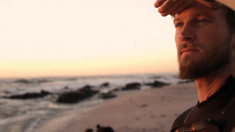 surfista masculino protegiendo los ojos en la playa 4k
