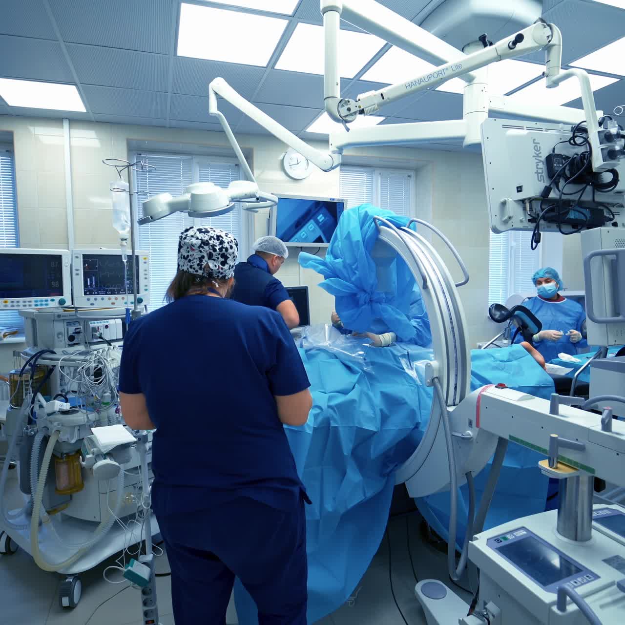 Team of surgeons performing operation in bright modern surgery room. Operating theatre. Modern equipment in clinic.