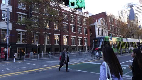 people crossing street near tram and buildings