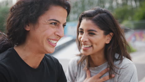 two female friends meeting in urban skate park