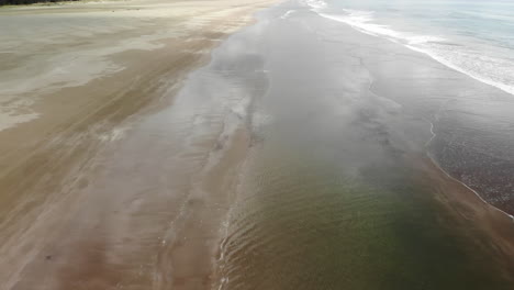 Clouds-Reflection-On-The-Beach-With-Golden-Sandy-Seashore-In-Porangahau,-North-Island,-New-Zealand