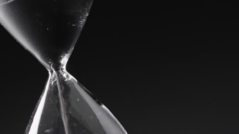 Video-of-hourglass-with-sand-pouring,-copy-space-on-black-background