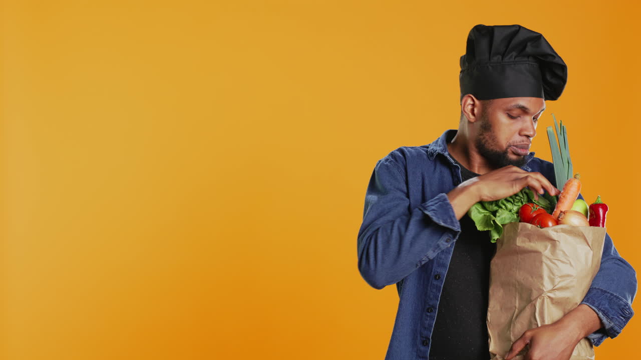 cocinero afroamericano examinando sus comestibles en una bolsa de papel