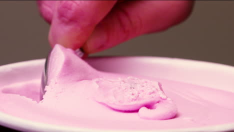 close-up scooping pink, cherry ice cream from a container