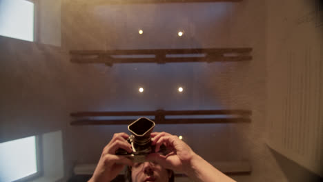 vintage medium format camera viewed through glass with reflection of person