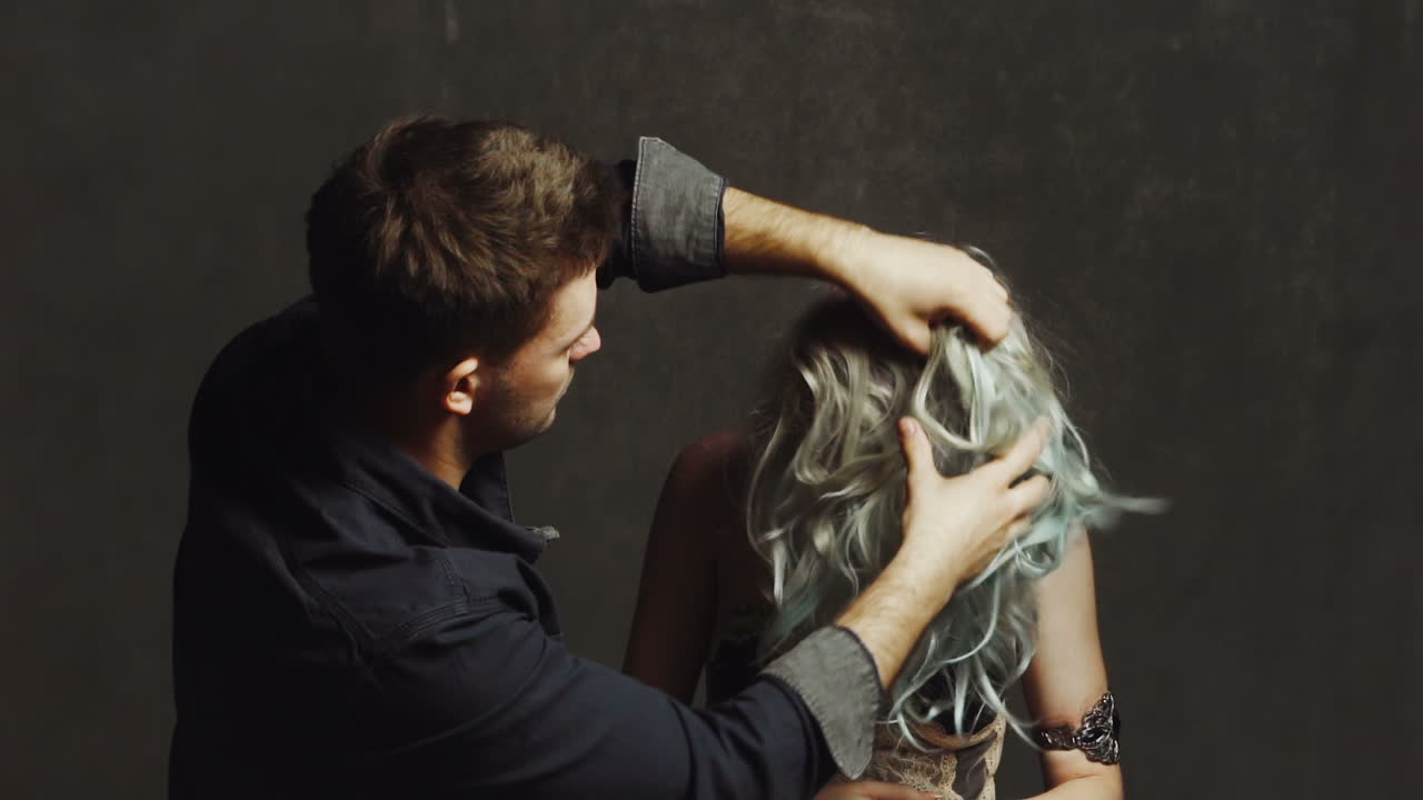 Man combing woman in studio. Hairdresser combing hair of woman in studio