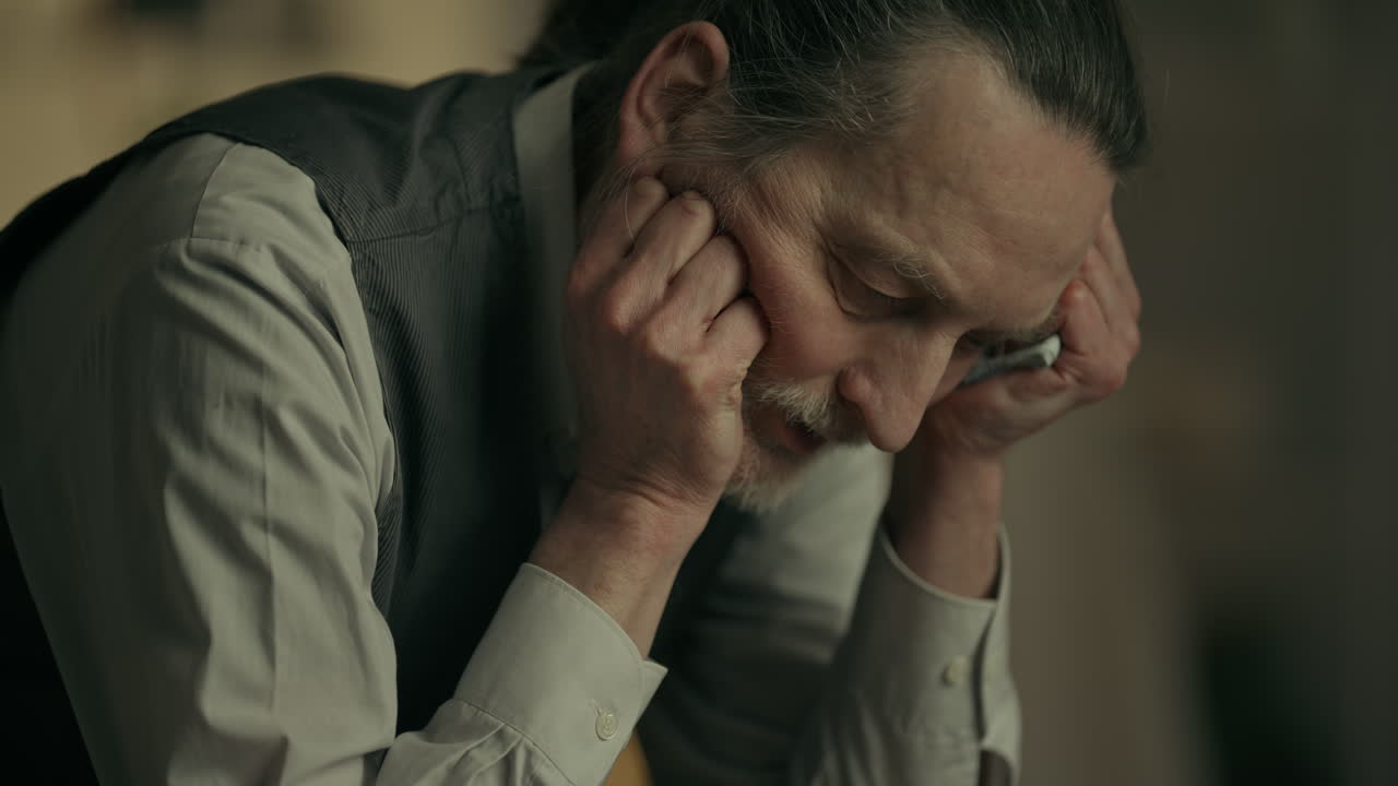 Primo piano di un triste uomo anziano che si tiene la testa
