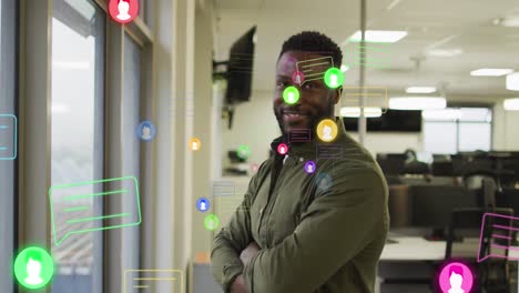 Animation-of-profile-and-message-icons-over-african-american-man-with-crossed-arms-smiling-at-office