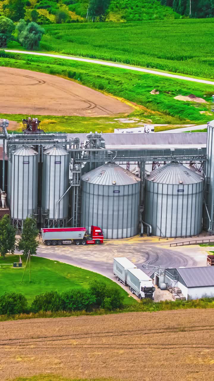 A factory with storage and silos where trucks unload. Aerial time lapse shot