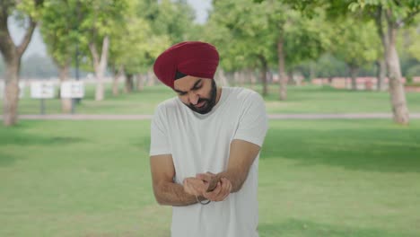 sick sikh indian man suffering from hand pain in park