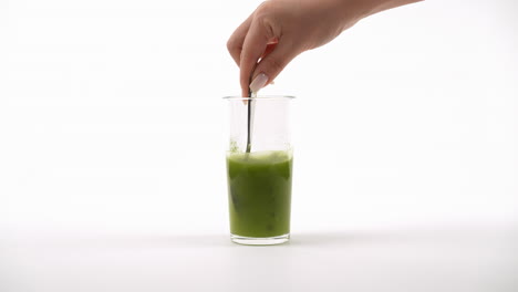 vidrio transparente con polvo verde que se mezcla con un tenedor, creando burbujas en un entorno blanco