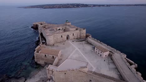 Inclinación-Aérea-Hacia-Abajo-Castillo-Isla-De-Ortigia-Al-Atardecer,-Sicilia-Italia