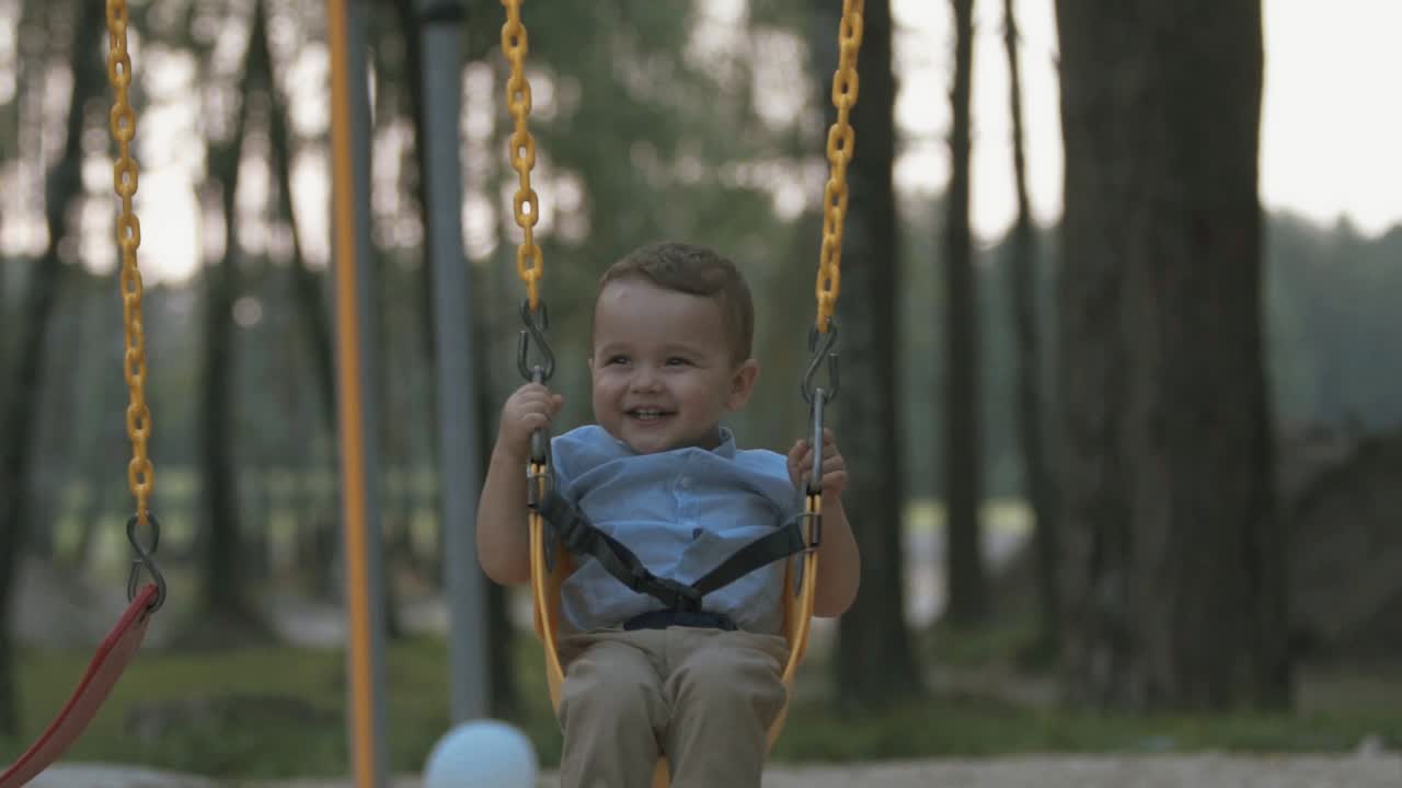 el bebé feliz viaja en un columpio en cámara lenta