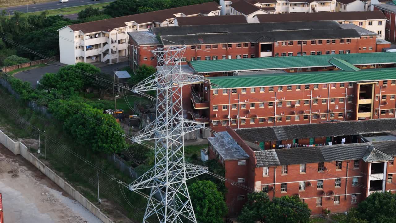 Drone clip of power lines in front of a group of low cost flats or units where people live in a crowded environment in an urban area