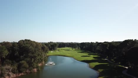 Sie-Fliegen-über-Baumwipfel-Und-Zeigen-Ein-Spektakuläres,-Lebendiges-Golfplatzfeld