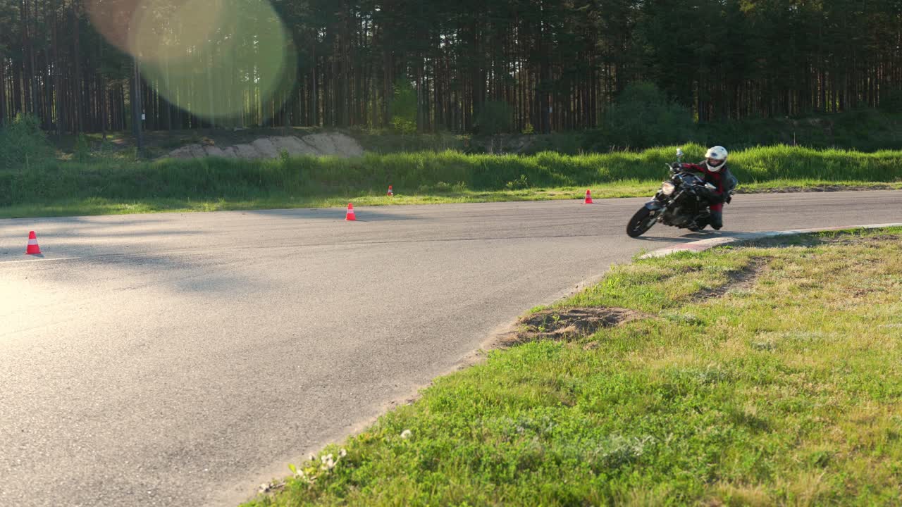 Motociclista che guida al tramonto con bagliore solare sul tracciato.