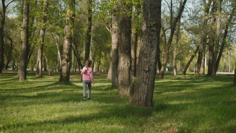 una niña alegre salta y corre por el césped en el parque de primavera