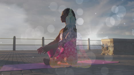 manchas blancas de luz cayendo contra la mujer afroamericana en forma realizando yoga en el paseo marítimo
