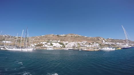 Summer-in-Mykonos-island,-Greece-with-yachts-in-the-harbor-and-luxury-white-waterfront-houses-and-hotels