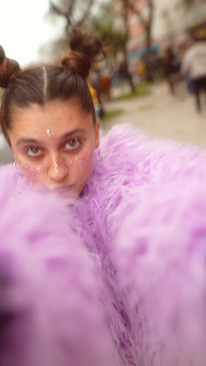 Giovane donna gioiosa con brillantini sul viso e un cappotto viola che si fa un selfie