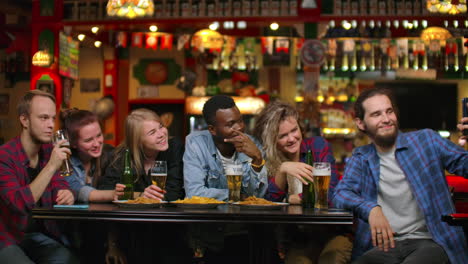 In-the-Bar-or-Restaurant-Hispanic-man-Takes-Selfie-of-Herself-and-Her-Best-Friends.-Group-Beautiful-Young-People-in-Stylish-Establishment.