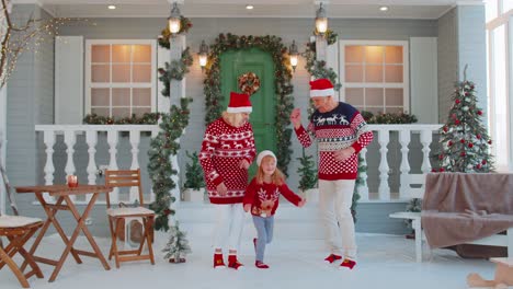 Feliz-Pareja-De-Ancianos-Abuelos-Con-Nieta-Celebrando-Bailando-Cerca-De-La-Casa-De-Navidad