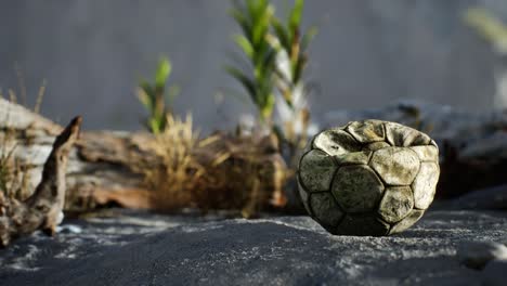 una vieja pelota de fútbol rota arrojada yace en la arena de la playa del mar