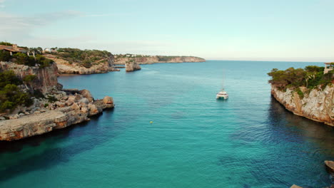 catamarán en aguas cristalinas con vistas a las es pontas en cala llombards, mallorca, españa