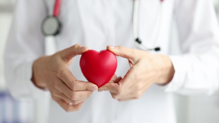 A doctor holding a red heart, symbolizing heart health and care