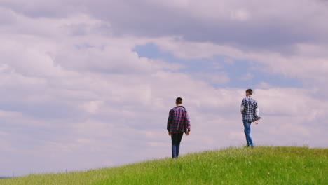 two young teenage boys run along the green hill