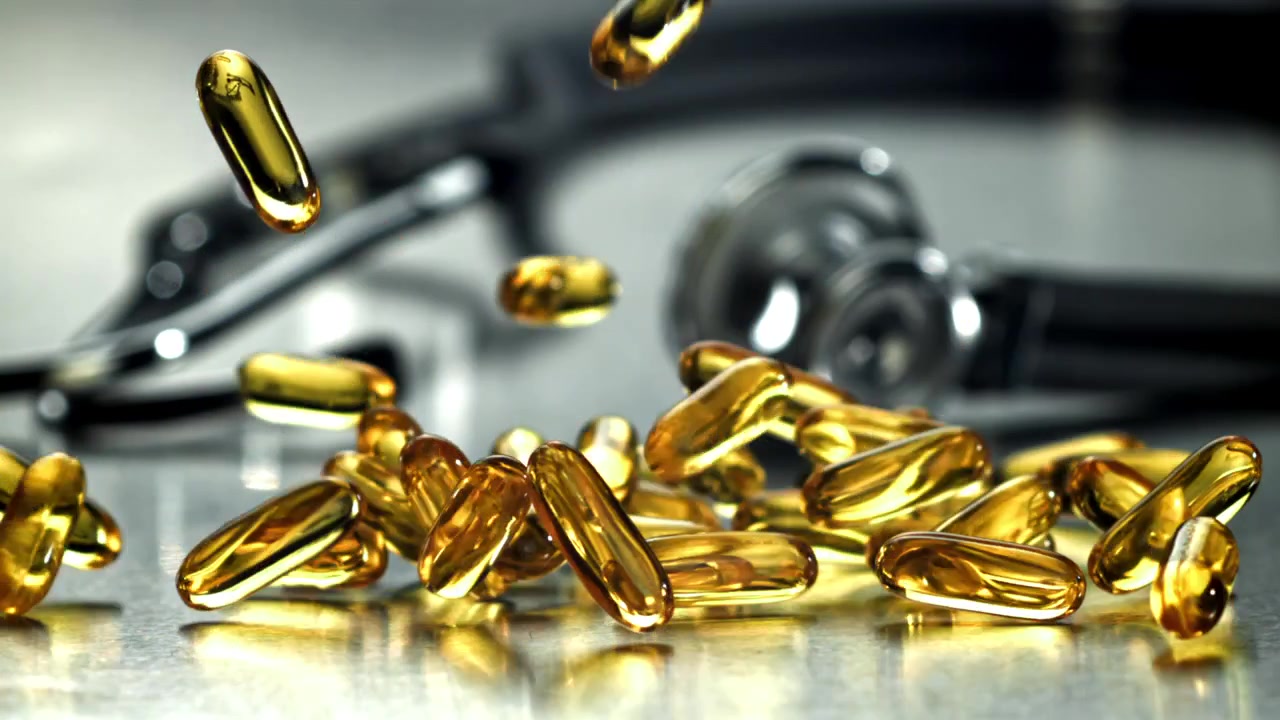 Capsule Omega-3 dorate in caduta al rallentatore con stetoscopio