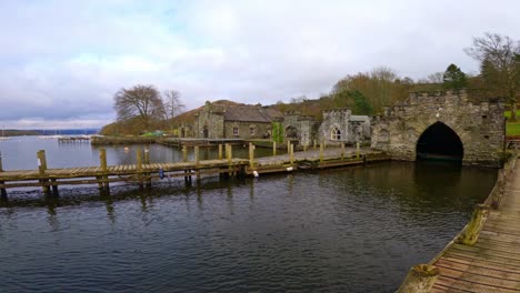 lake windermere in the english lake district, with its iconic wooden jetty, historic stone-built buildings, and moody grey skies