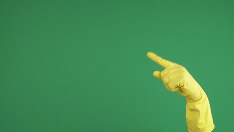 female hand with blue protective rubber glove pointing up with finger over empty chroma key green screen background. hand gesture. 4 k video