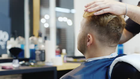 A-Young-Man-Is-Done-With-Hair-Styling-In-The-Salon-Rear-View