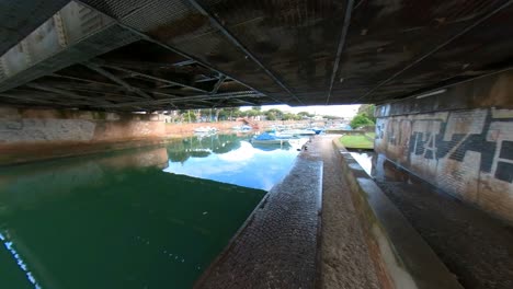 boats moored along a canal under a bridge