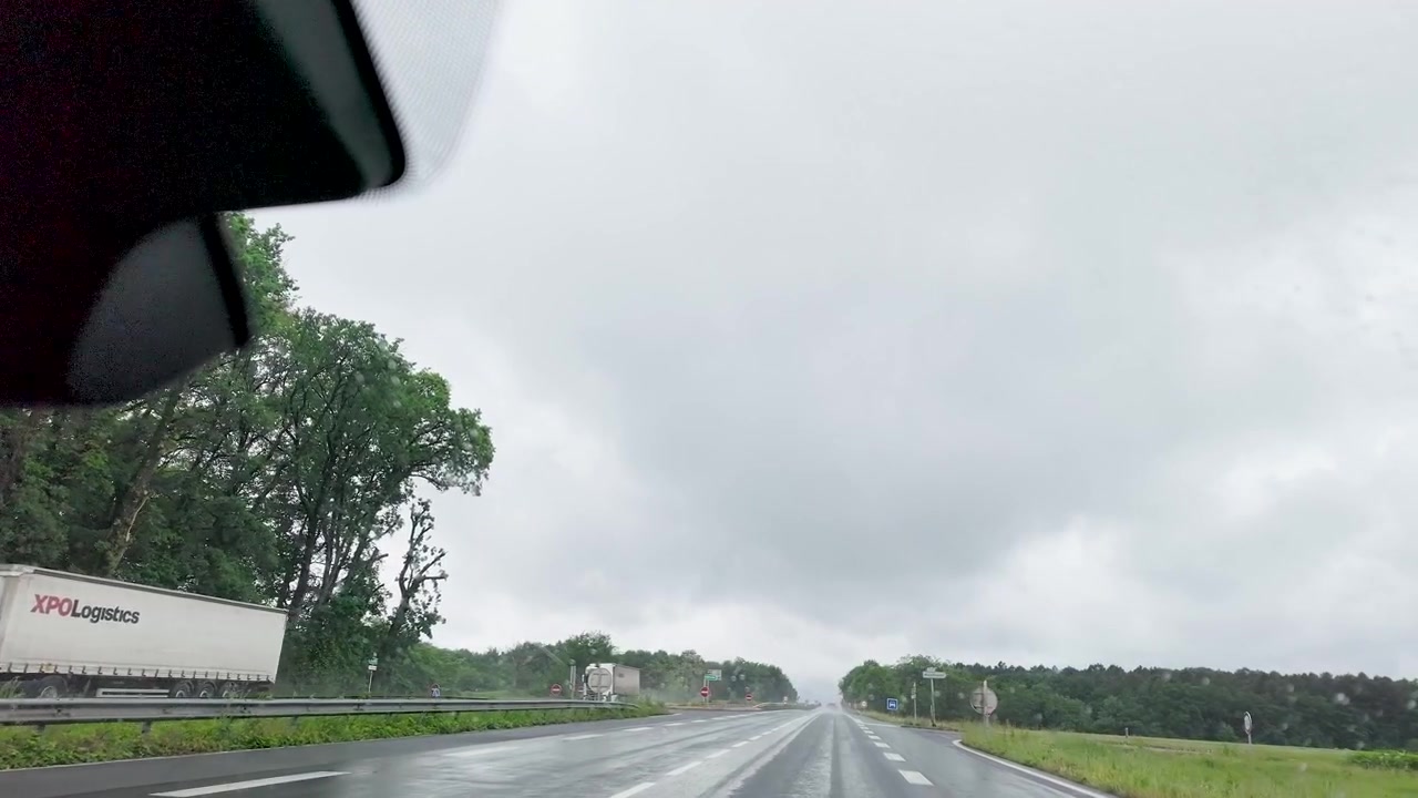 Ripresa in soggettiva da un'auto che guida su un'autostrada bagnata durante un tempo piovoso.
