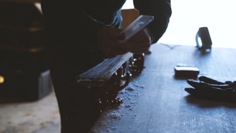 person waxing skis, scraping wax off of ski after ironing