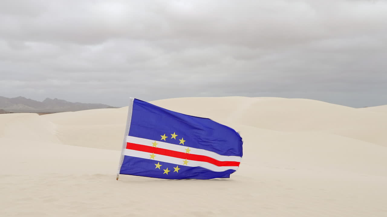 The Cape Verde flag flies in the Viana Desert at overcast day, Boa Vista island, Cape Verde