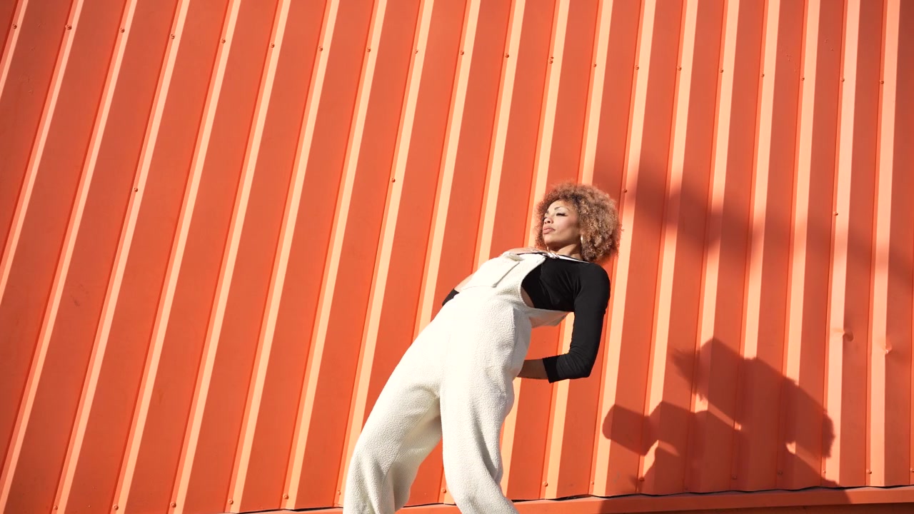 En moderne model poserer mod en lys og levende orange baggrund